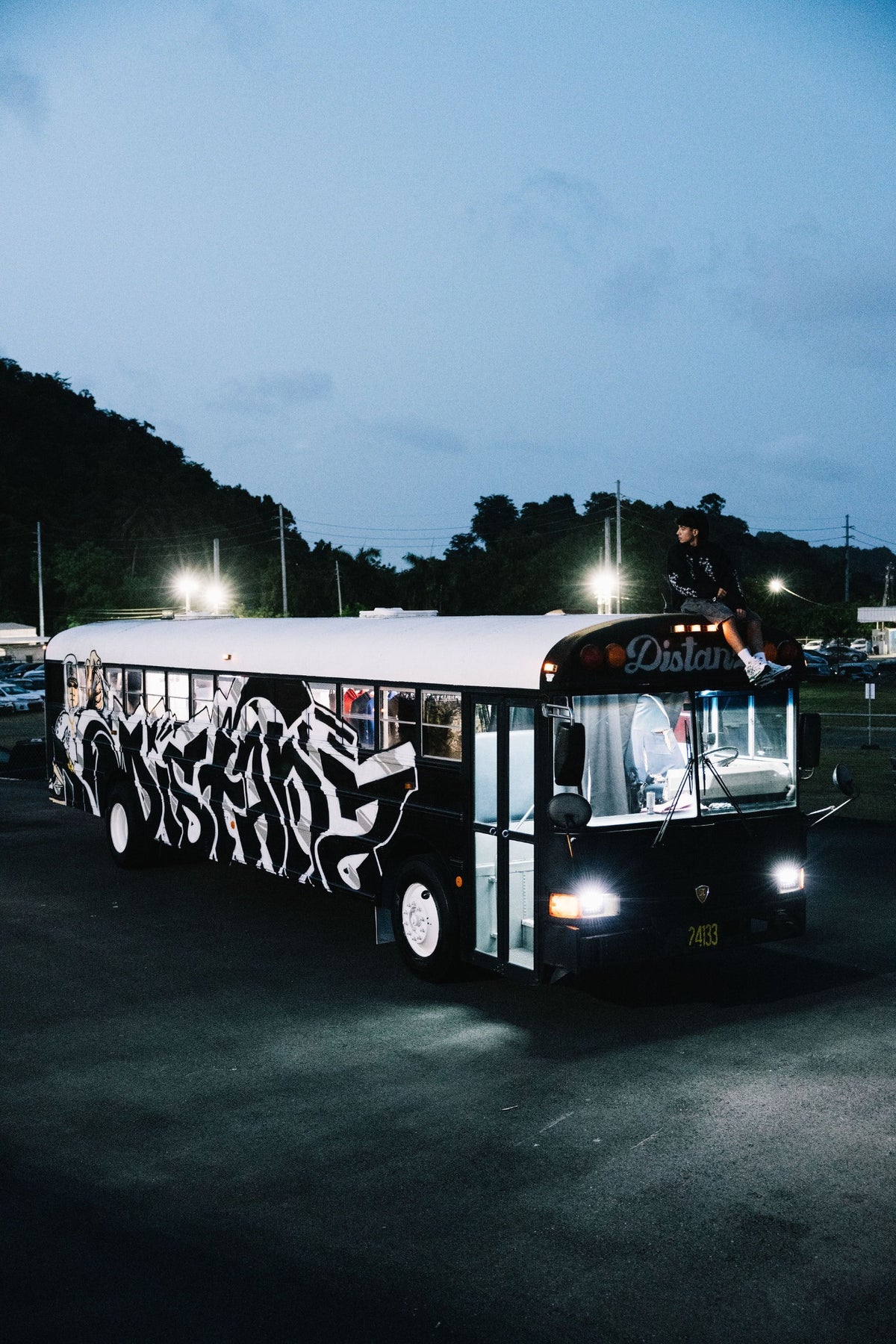 DISTANZ school bus at night with a person sitting on top